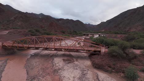 a rusty bridge over a dry riverbed in the scenic route 68, quebrada de las conchas, salta, aerial view