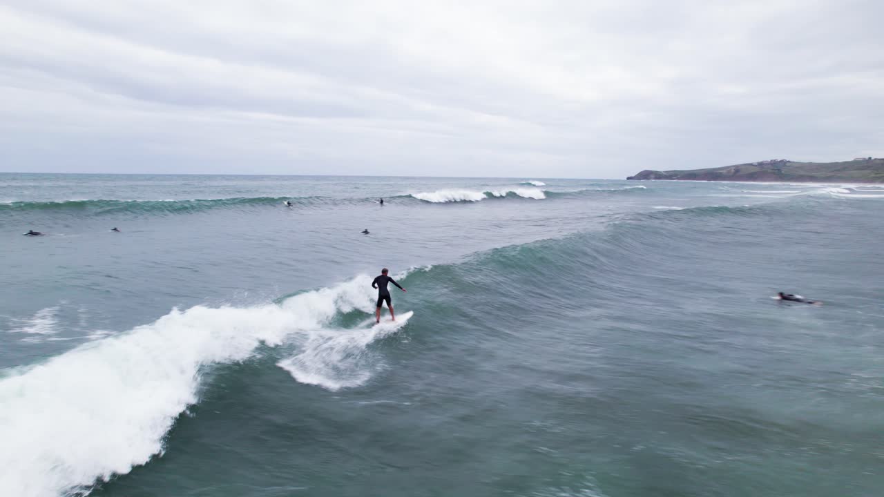 toma aérea de surfistas montando olas altas en playa meron en san vicente de la barquera