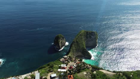 drone footage capturing a wide aerial orbit of kelingking beach in bali, indonesia, highlighting the turquoise waters, dramatic cliffs, and the surrounding landscape