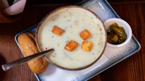 a bowl of creamy soup with croutons and a side of bread