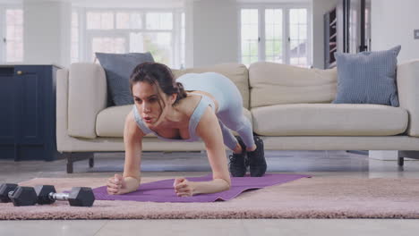 Mujer-Vestida-De-Fitness-En-Casa-En-El-Salón-Haciendo-Estiramientos-Y-Haciendo-Ejercicio-Con-Pesas-De-Mano---Filmada-En-Cámara-Lenta