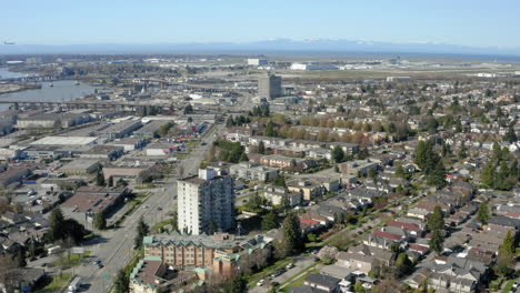 aerial flying over south vancouver toward the yvr airport as a plane flies in to land