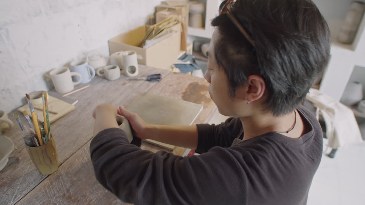 Asian Ceramist Shaping Clay on Pottery Wheel