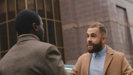 close-up view of caucasian and african american businessman in elegant clothes talking about business and arguing in the street in autumn