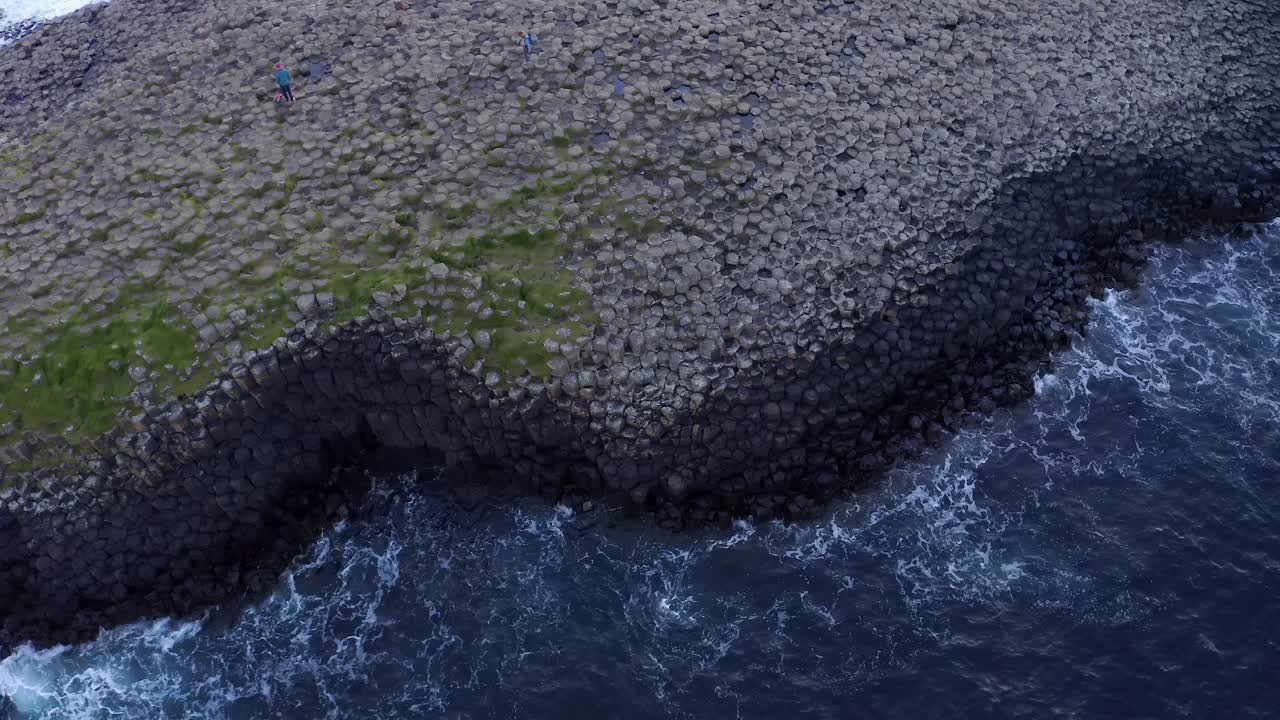 Slow-motion aerial with a rotating top-down view of Giant's Causeway and calm waves