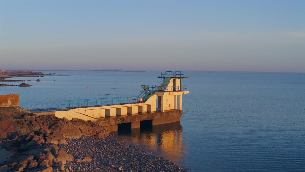 Aerial orbit of Blackrock diving board on a sunny evening, showcasing Salthill's coastline