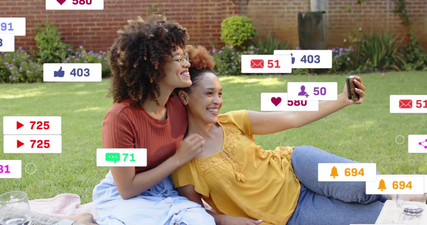 Couple lifting smartphone and starting live social stream to share picnic generating reaction icons