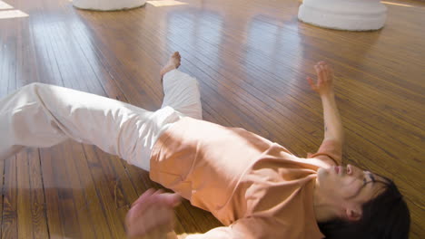 focused young man in casual wear performing a contemporary dance on the floor in the studio