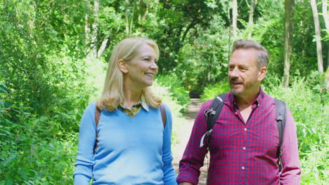 mature couple in countryside hiking along path through forest together