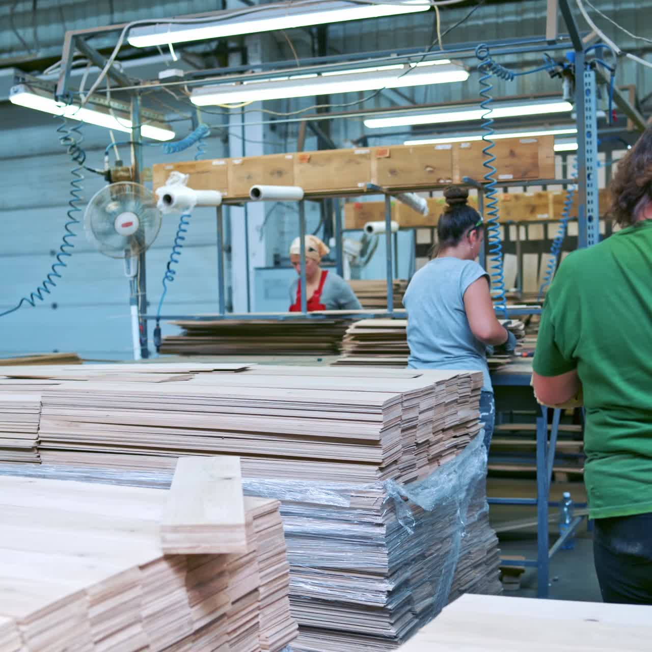 Workers processing wood planks in a factory setting