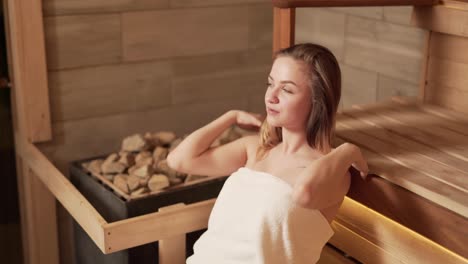 bella chica envuelta en una toalla relajándose en una sauna rusa