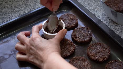 baker with a molder is making cookies made of cocoa and seeds