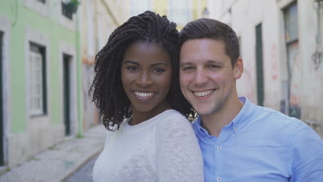 una pareja multirracial feliz mirando a la cámara.