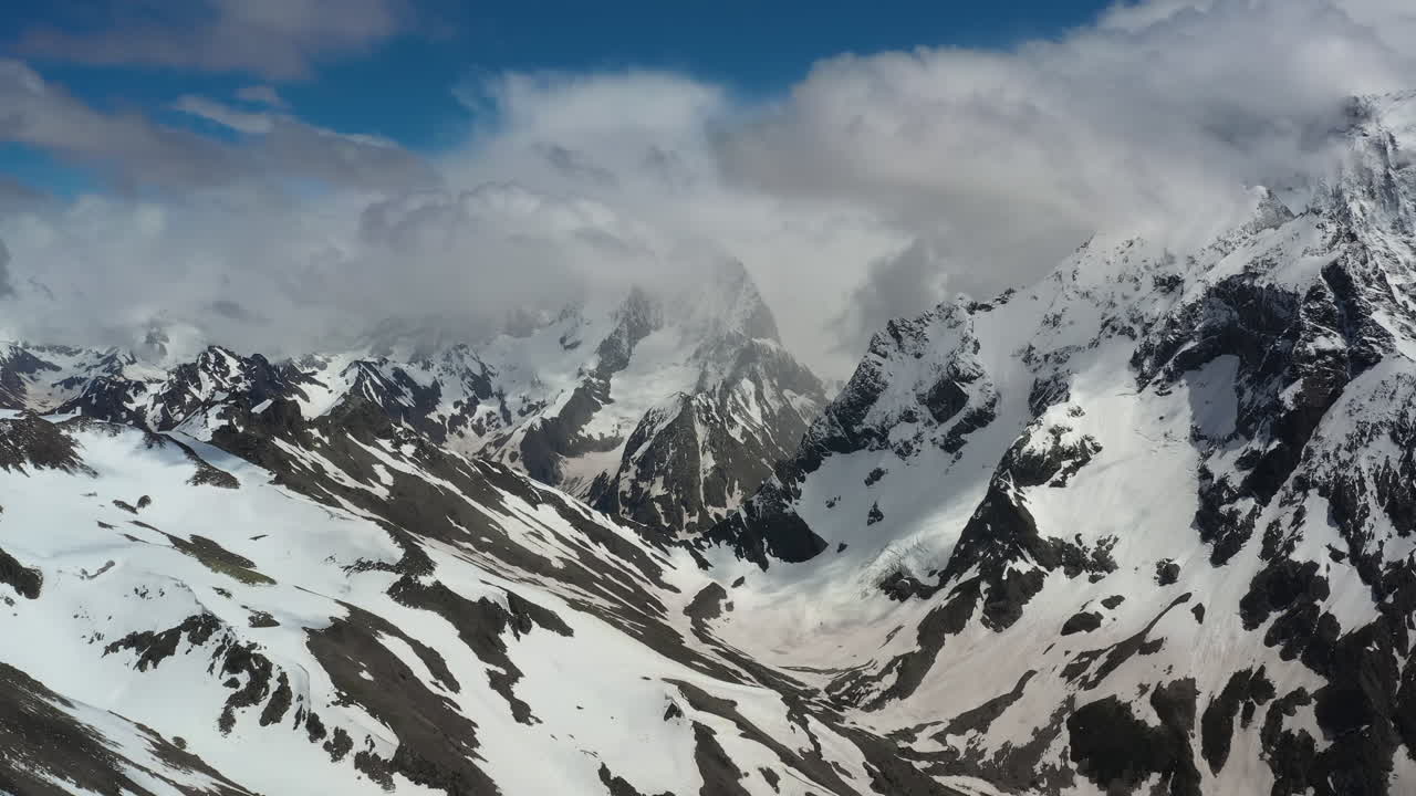 воздушный полет сквозь горные облака над прекрасными заснеженными вершинами гор и ледников.