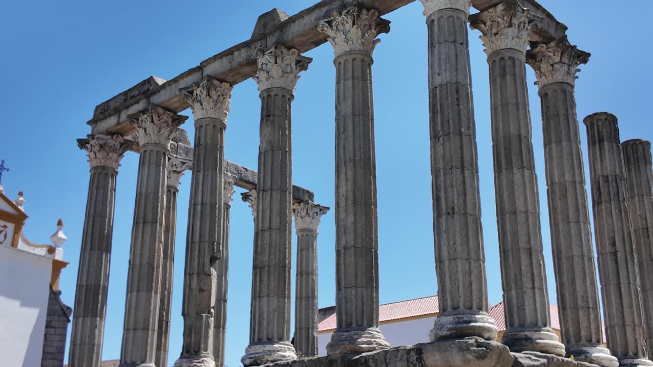 Corinthian granite columns of the Roman Temple of Evora in Portugal, also known as Temple of Diana, bathed in sunlight under a clear blue sky