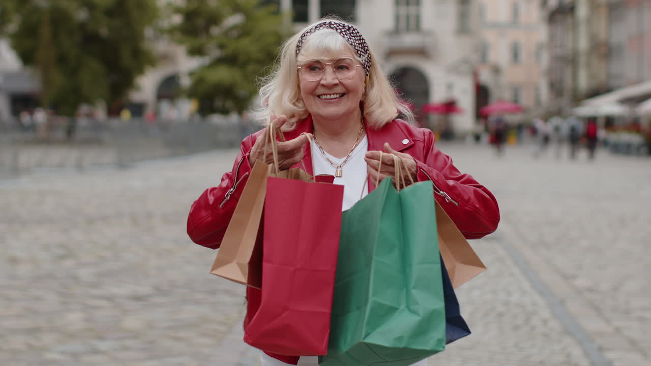 mujer mayor feliz adicta a las compras consumidor después de la venta de compras con bolsas llenas caminando por la calle de la ciudad