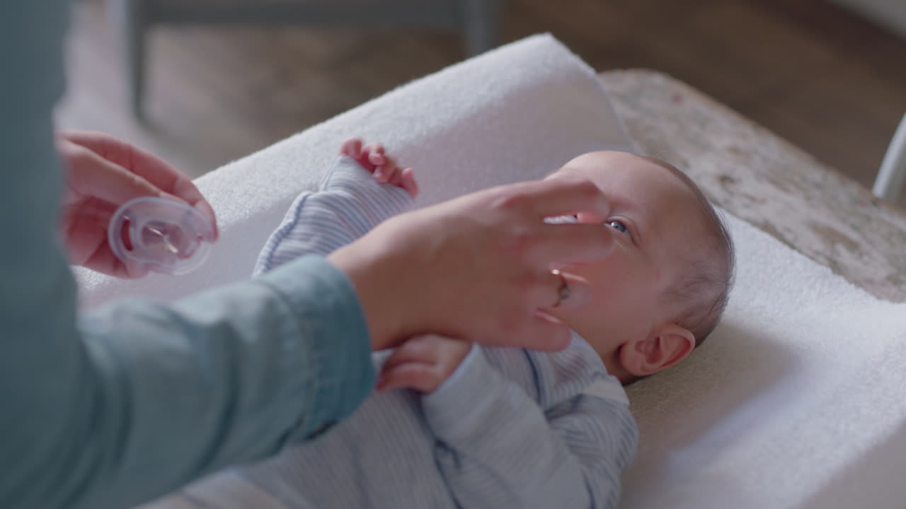 Mother giving baby pacifier cute toddler sucking on dummy with loving mom caring for newborn at home enjoying motherhood Premium Stock Video Footage