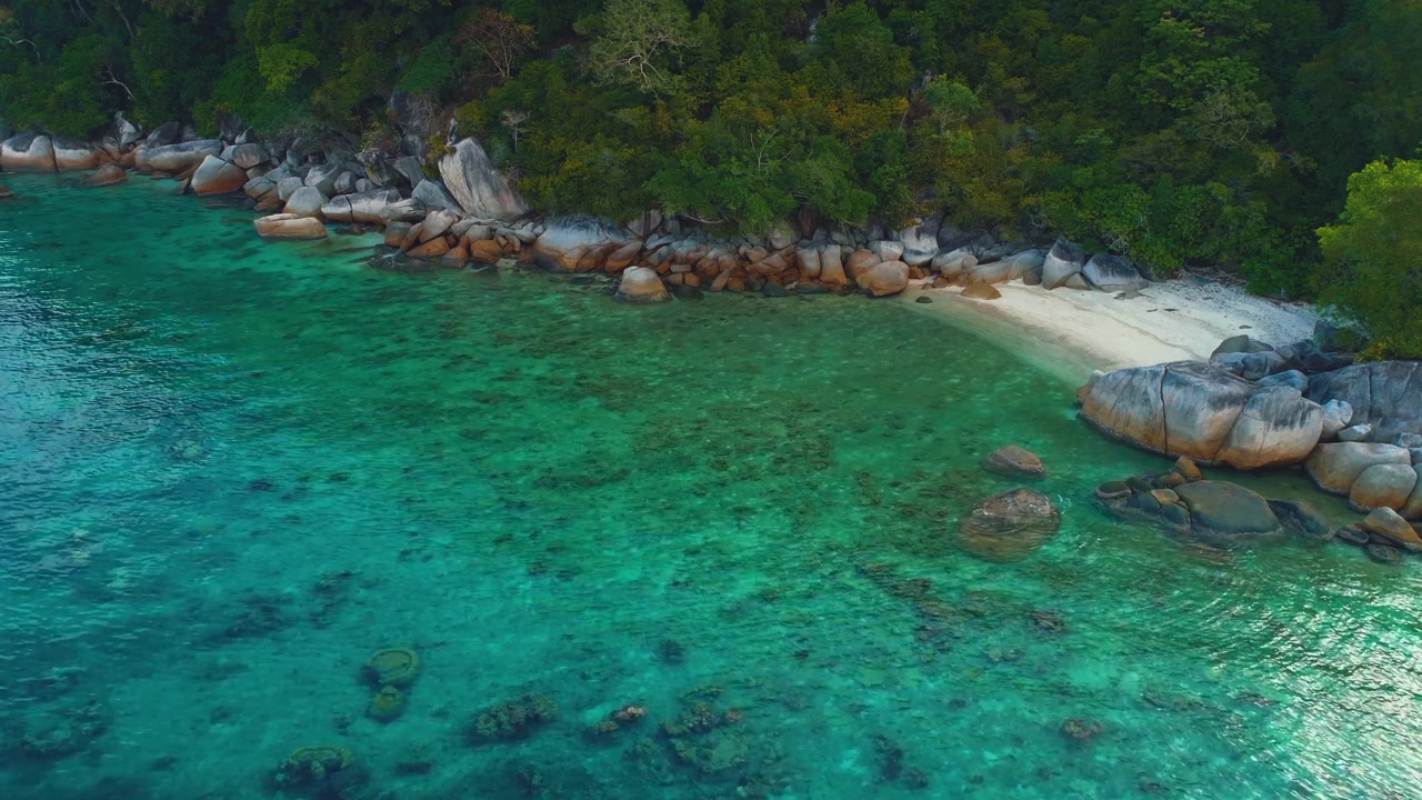 The coastline of beautiful remote Island in South East Asia (Malaysia) seen from above. The clear blue water is moving gently.