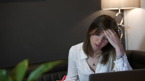 Overworked-stressed-young-business-woman-struggling-with-debts-and-paperwork-working-at-home-in-front-of-laptop-in-kitchen