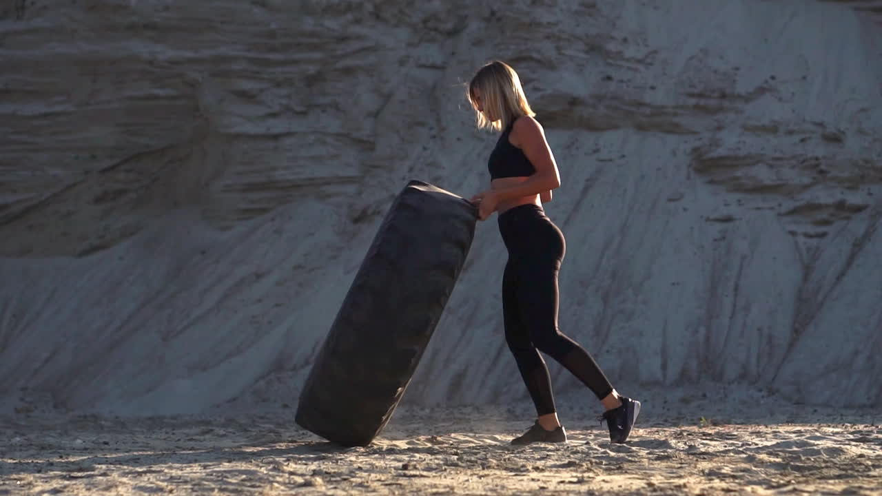 Girl on sand quarry pushing wheel in training crossfit workout