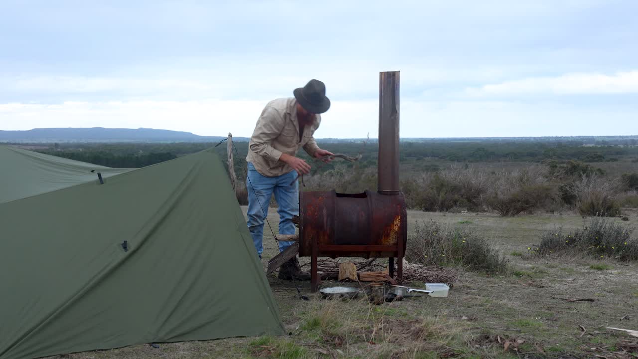 오스트레일리아 사막의 부쉬맨이 오래된 학교의 불 드럼으로 불을 피우고 있습니다.