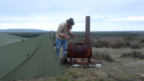 a bushman in the australian desert making a fire with a an oldschool fire drum