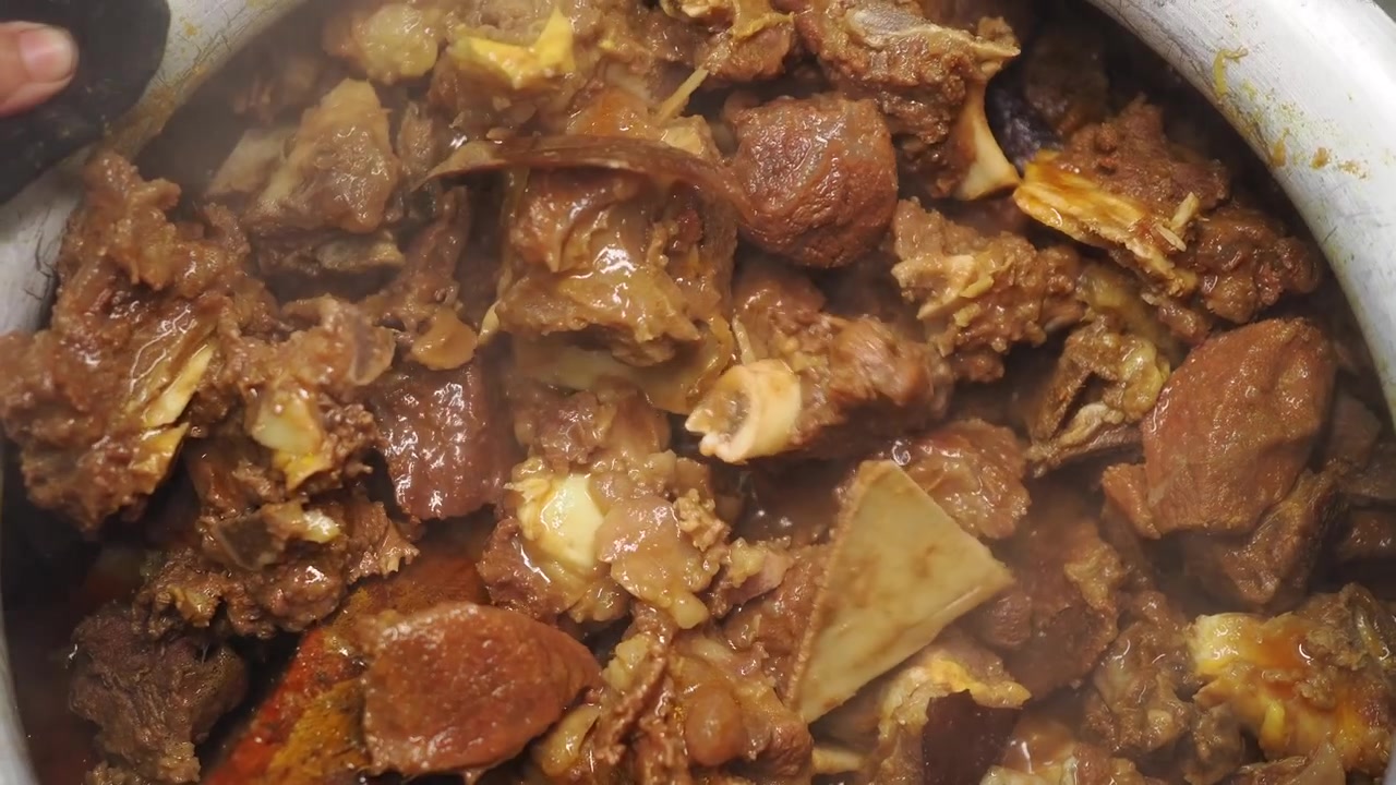 Mescolando curry di montone tradizionale in una grande pentola