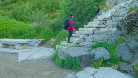 following shot of an asian tourist walking up the famous sheppard stairs in lofoten to the peak of reinebringen