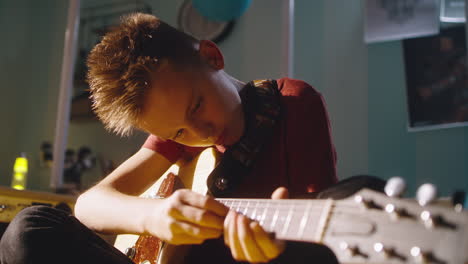 boy playing electric guitar in his bedroom
