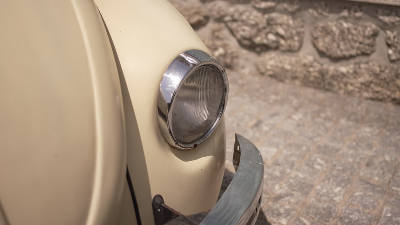 Close up of a vintage Volkswagen Beetle headlight with a classic chrome finish.