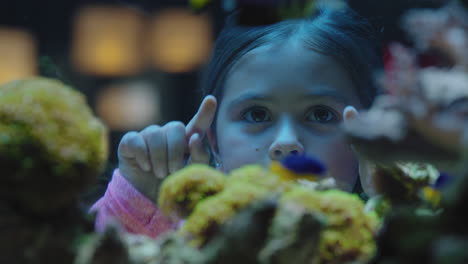 happy girl in aquarium looking at fish curious child watching colorful marine life swimming in tank learning about sea animals in underwater ecosystem inquisitive kid at oceanarium