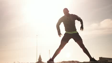 Man-performing-stretching-exercising-on-the-beach