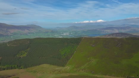 Mountain-walker-stopped-on-high-path-overlooking-deep-valley-and-misty-mountains-beyond-at-golden-hour