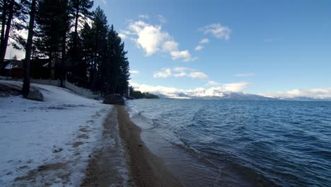 calm waves on a winter day in lake tahoe california with snow on the ground, handheld stable shot