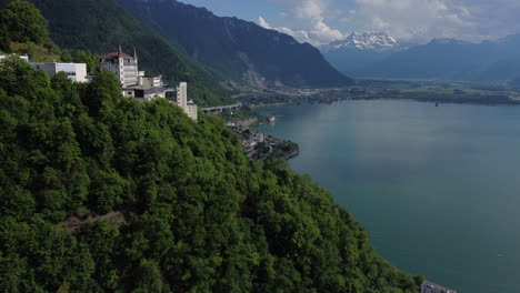 expansive aerial shot next to the green mountainside of montreux, switzerland with lake geneva in view