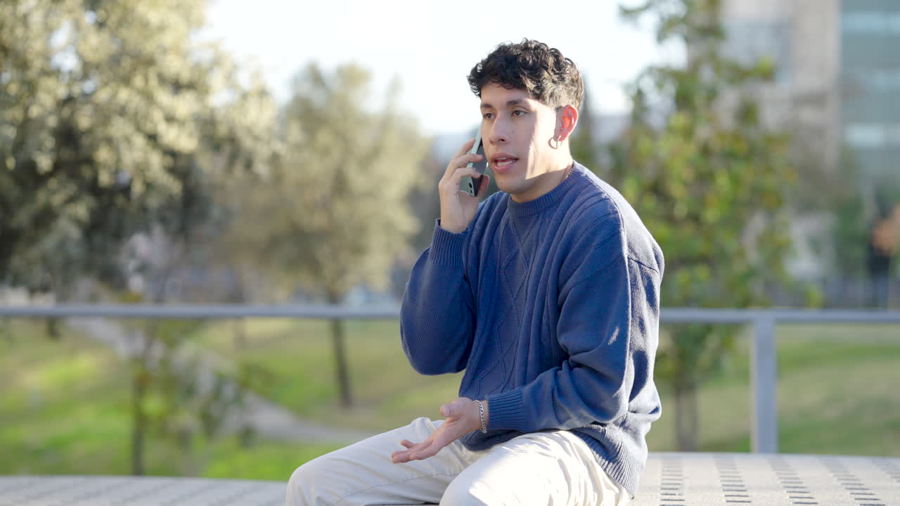 Young man receiving bad news on phone in park