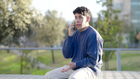 young man receiving bad news on phone in park