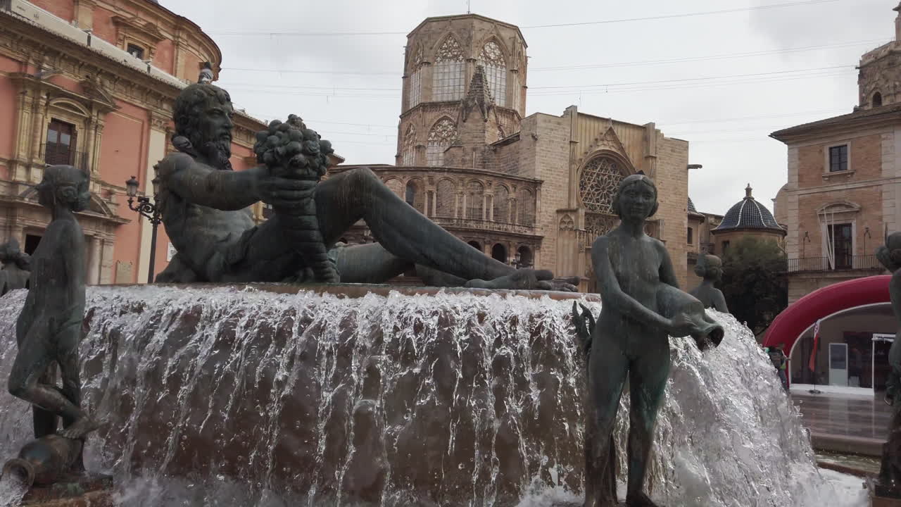 Valencia, Spain - October 25, 2021: In the heart of Valencia, visitors admire the intricate details of the fountain featuring playful sculptures. The surrounding historic buildings add to the charm of this central square