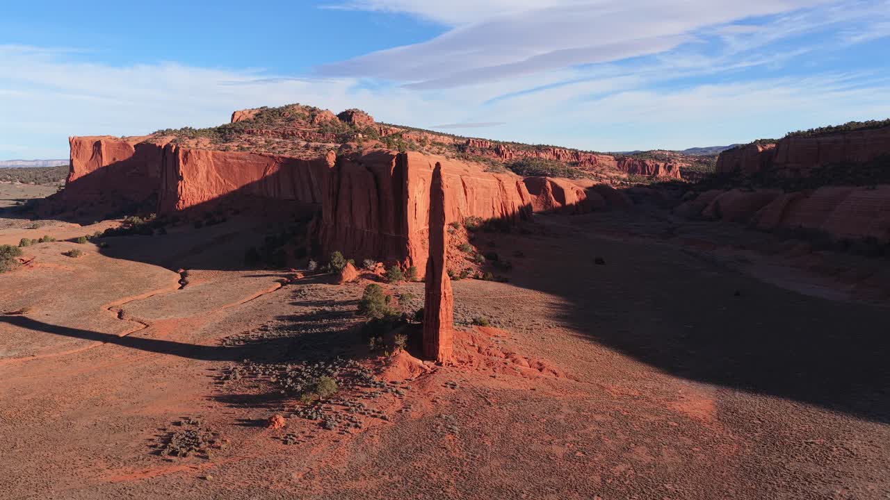 An aerial drone rotation moves slowly around a mysterious red stone spire, highlighting the rugged textures and desolate terrain of a remote sci-fi world suitable for futuristic background plates