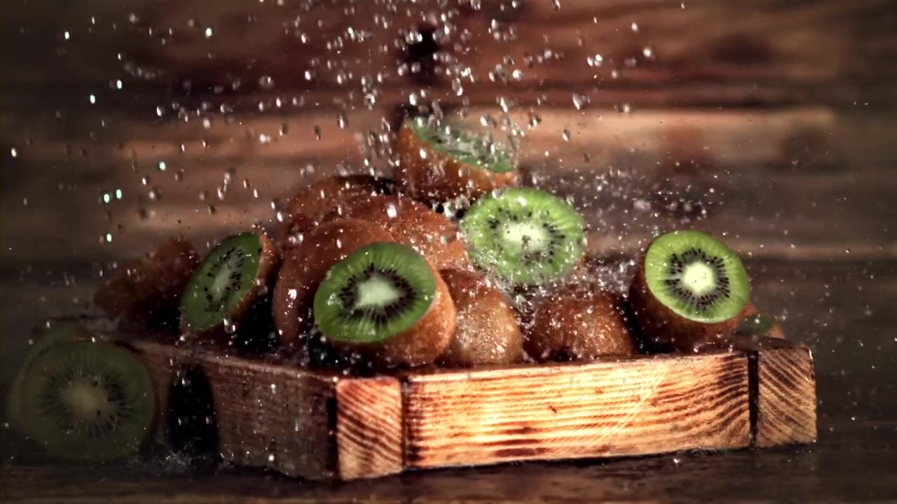 Acqua che schizza al rallentatore su kiwi freschi su un tagliere di legno
