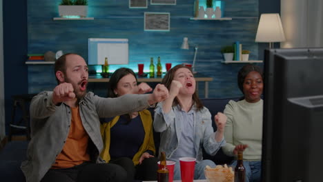 mixed race friends relaxing on couch while watching football game