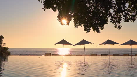 the view from a resort pool to the ocean in the distance is punctuated by open shade umbrellas in the midground