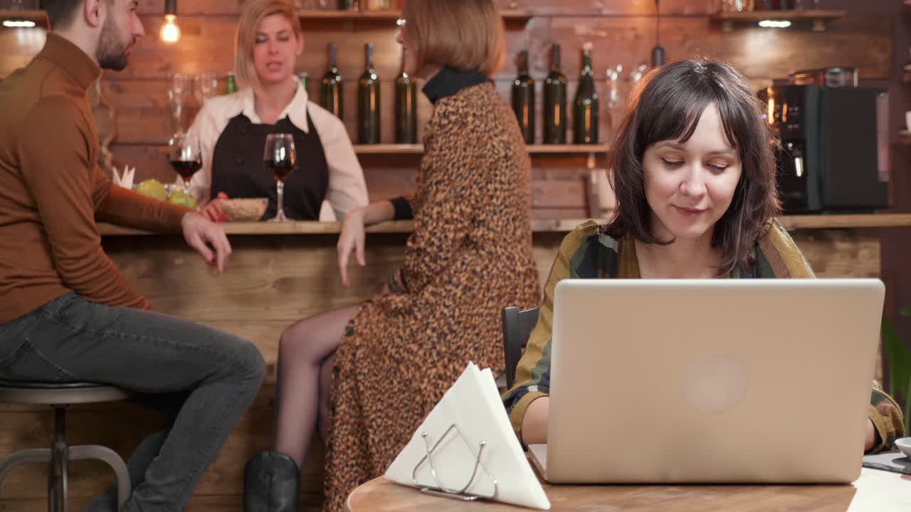 People in a bar using a laptop