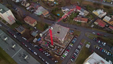 construction red crane helping to build a new multi-storey house with apartments in a residential area