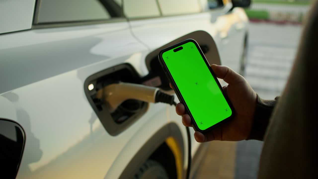 persona cargando un vehículo eléctrico con un teléfono inteligente