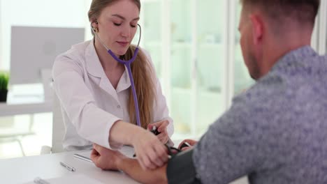 female doctor measures male patient's blood pressure in clinic