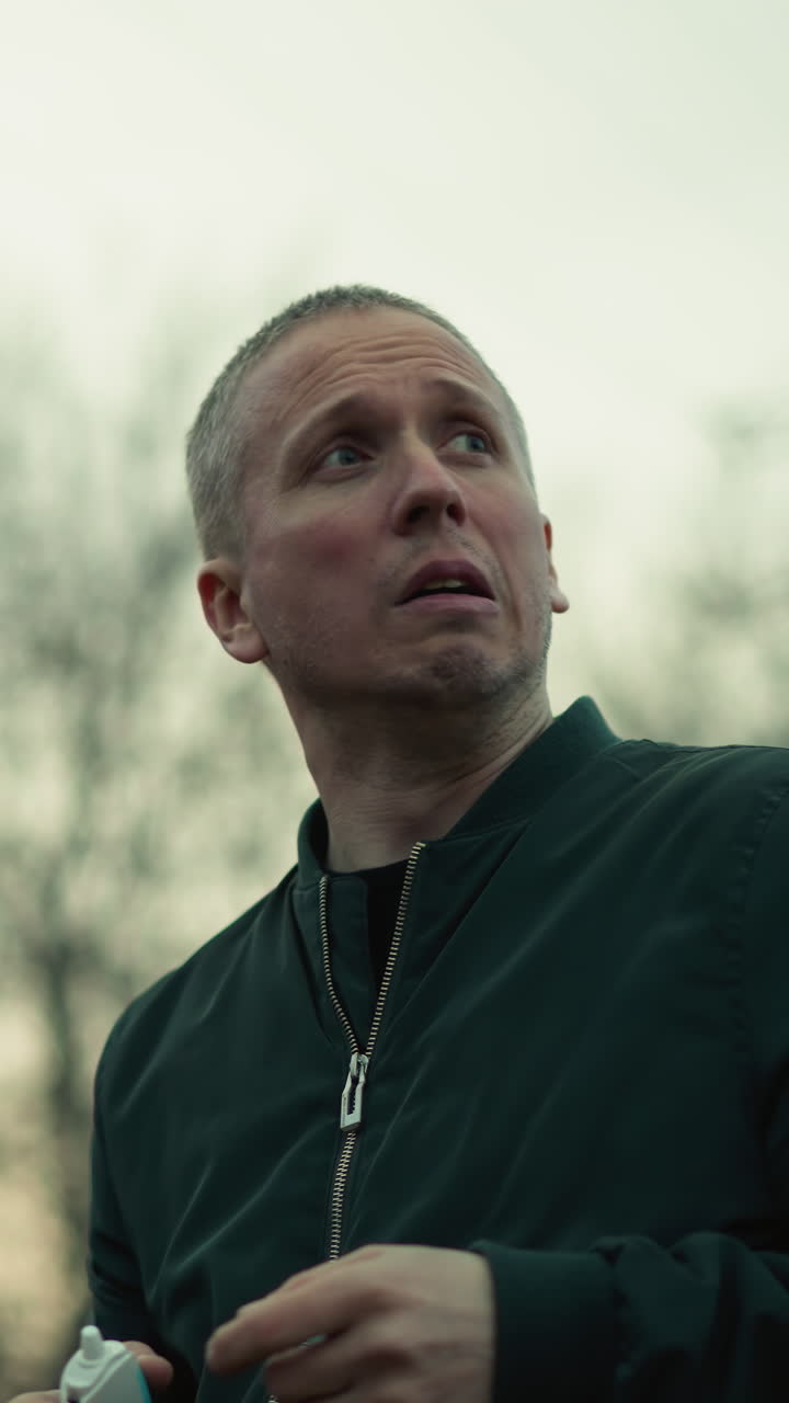 색 흡입기를 사용하는 남자의 근접한 모습, 나무의 배경과 하늘을 볼 수 있습니다.