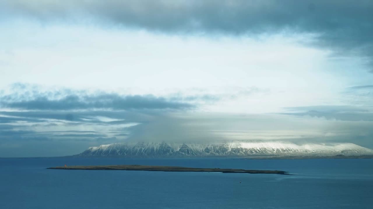 1월에 아이슬란드의 눈 덮힌 산을 가로질러 이동하는 구름 사이로 햇빛의 시간 경과