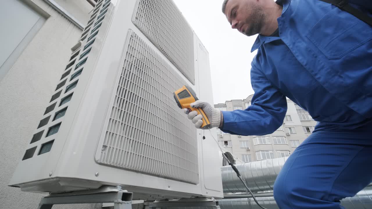 Technician uses a thermal imaging infrared thermometer to check the condensing unit heat exchanger