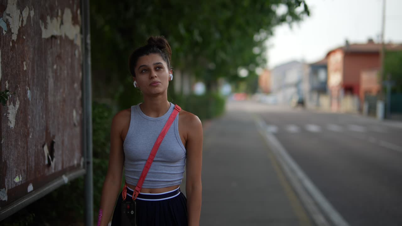 Young woman walking on the street by a bus stop